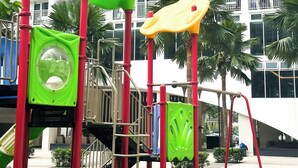 A playground with slides and climbing structures, surrounded by a white building with balconies and palm trees. - Crizzy's Hub Sariel @ Shore Residences (Pasay City, Metro Manila)