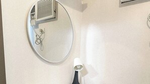 A small office space with a white desk, a clear plastic chair, and a round mirror on the wall. - Crizzy's Hub Sariel @ Shore Residences (Pasay City, Metro Manila)