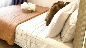 A neatly made bed with a brown blanket, white pillows, and a checkered duvet. There are three framed bird stamps on the wall. - Crizzy's Hub Sariel @ Shore Residences (Pasay City, Metro Manila)