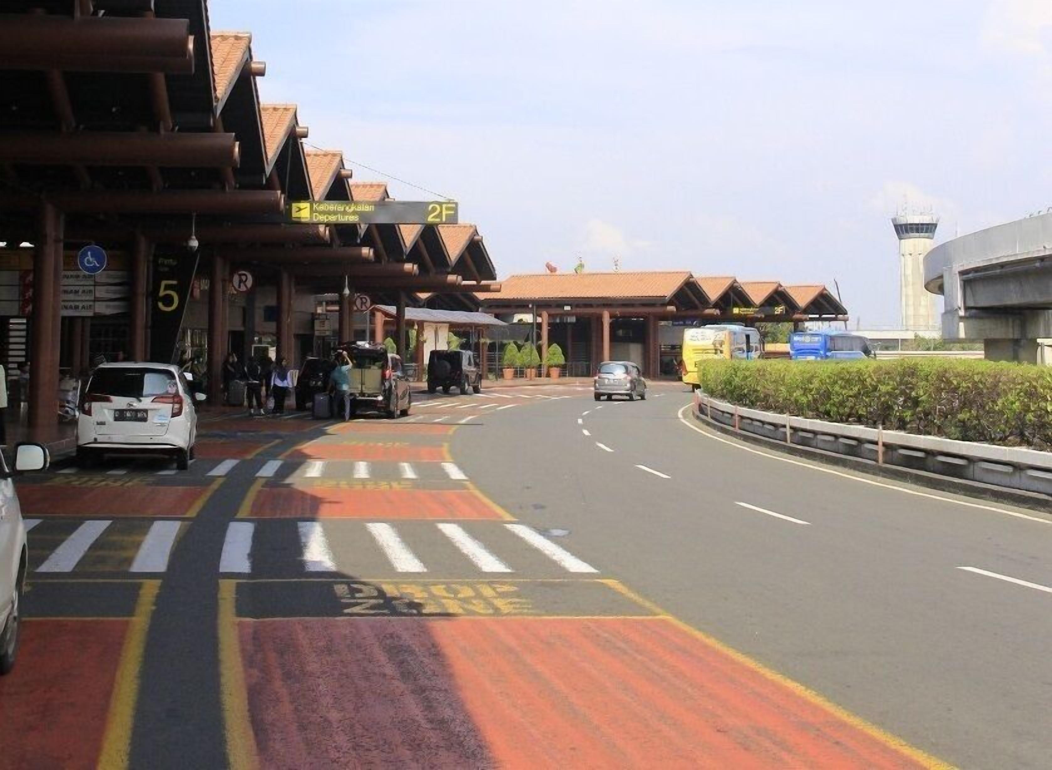 A road leading to a building with a sign indicating 'Departures' and a '2F' sign.