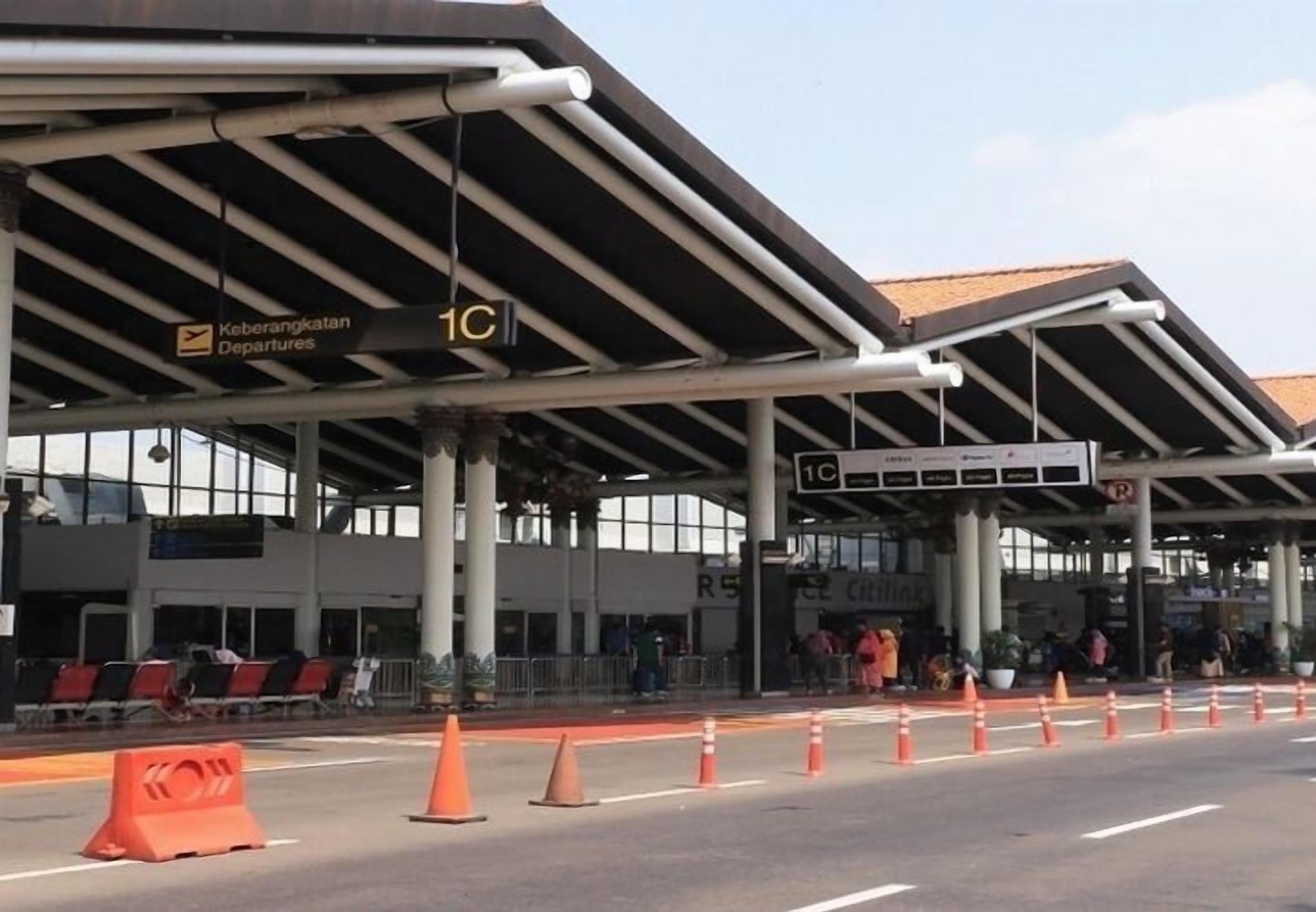 Um terminal de aeroporto com sinalização de embarque, balcão de check-in e área de espera coberta.