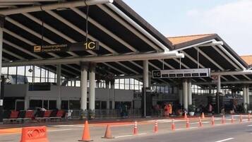 Um terminal de aeroporto com sinalização de embarque, balcão de check-in e área de espera coberta.