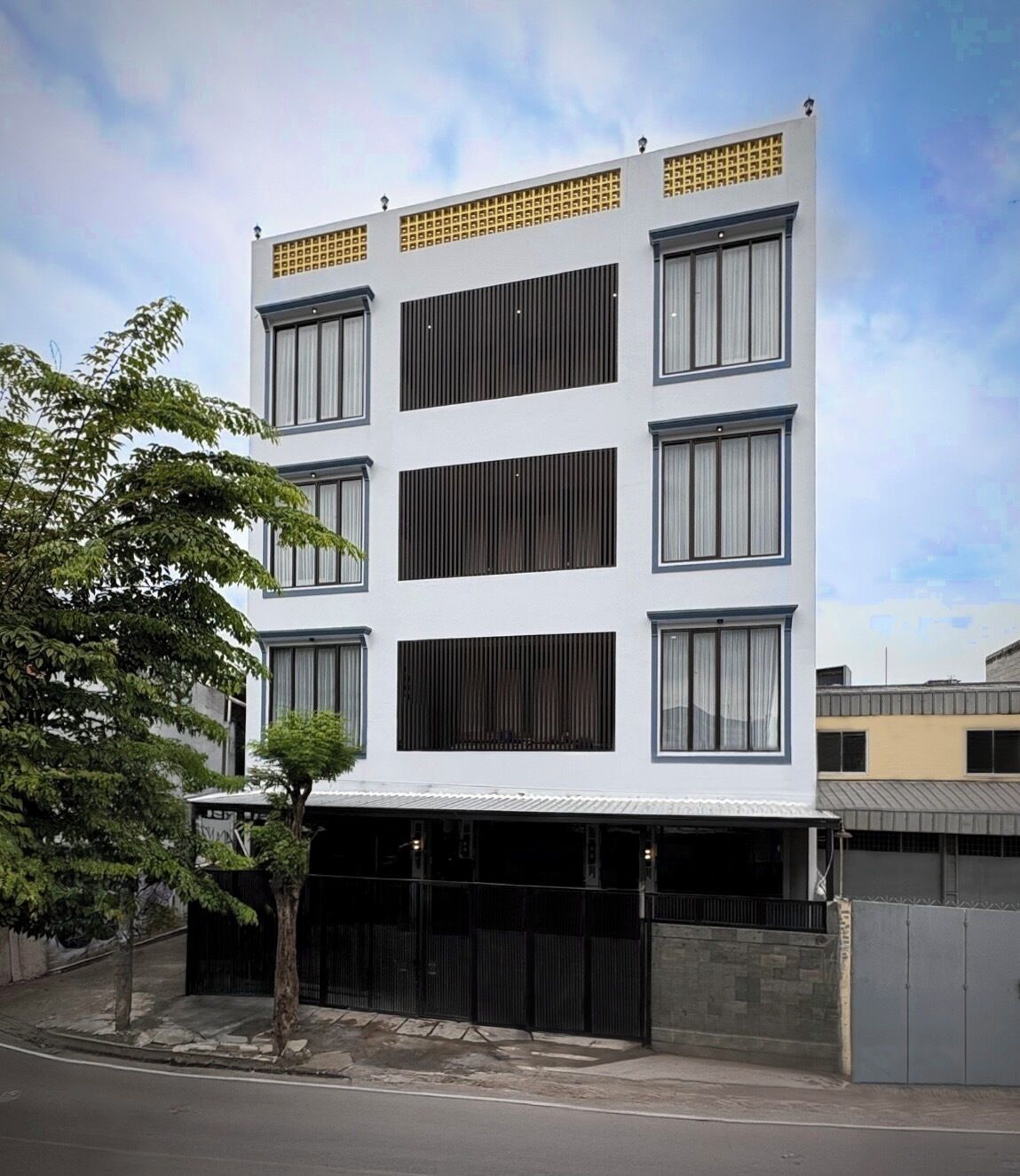 A modern multi-story building with a flat roof, large windows, and a gated entrance.