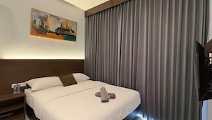 Quarto de hotel com cama, um quadro na parede e uma janela grande com cortinas.