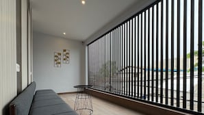 Quarto moderno com sofá cinza, uma mesinha redonda e vista através de uma grade de metal.