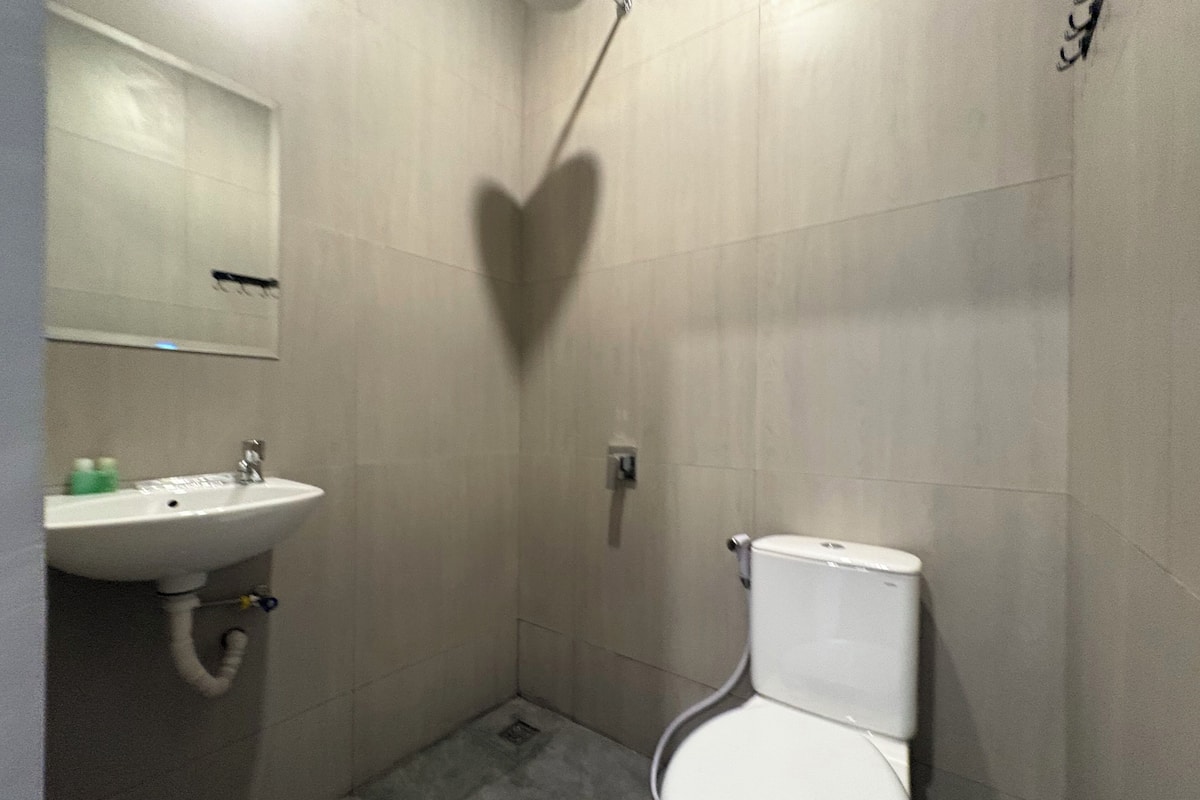 A small bathroom with a white sink, toilet, and shower.
