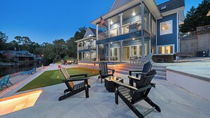 A modern two-story house with a large deck, outdoor seating, and a fire pit. - Heated Pool! MiniGolf! Hot Tub! Fire Pit! Lakefront! (Hot Springs)