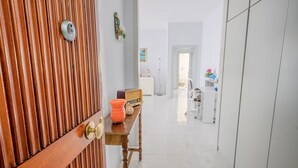 A hallway with a wooden door, a desk with a radio, and a chair. - MARINELLI HOUSE - Song'Parthenope - Naples (Napoli)