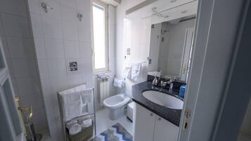 A modern bathroom with a black countertop sink, a white toilet, and a shower area.