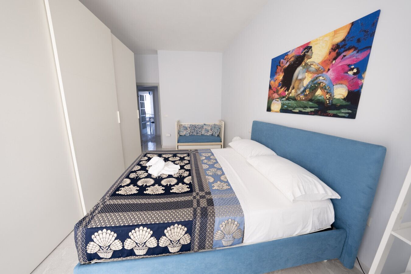 Un dormitorio con una cama, un cabecero azul y un cuadro en la pared.