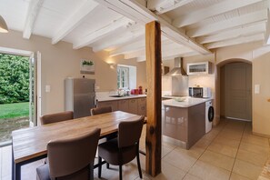 Una cocina con comedor, vigas de madera, lavadora y vistas al exterior.