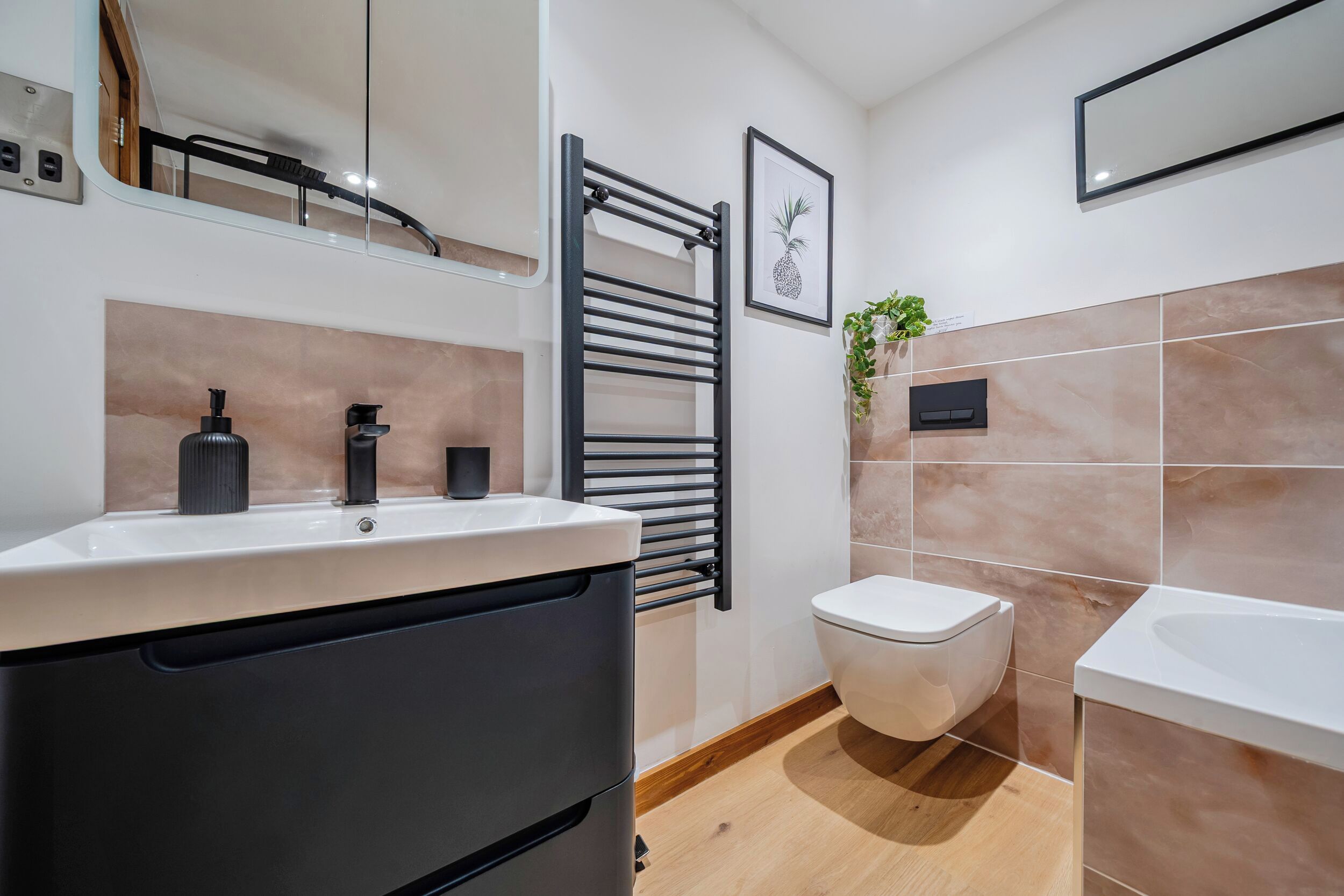 A modern bathroom with a white sink, black faucet, and a toilet.