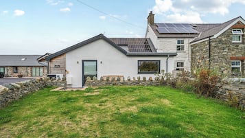 A two-story house with a stone facade, a sloped roof, and solar panels.