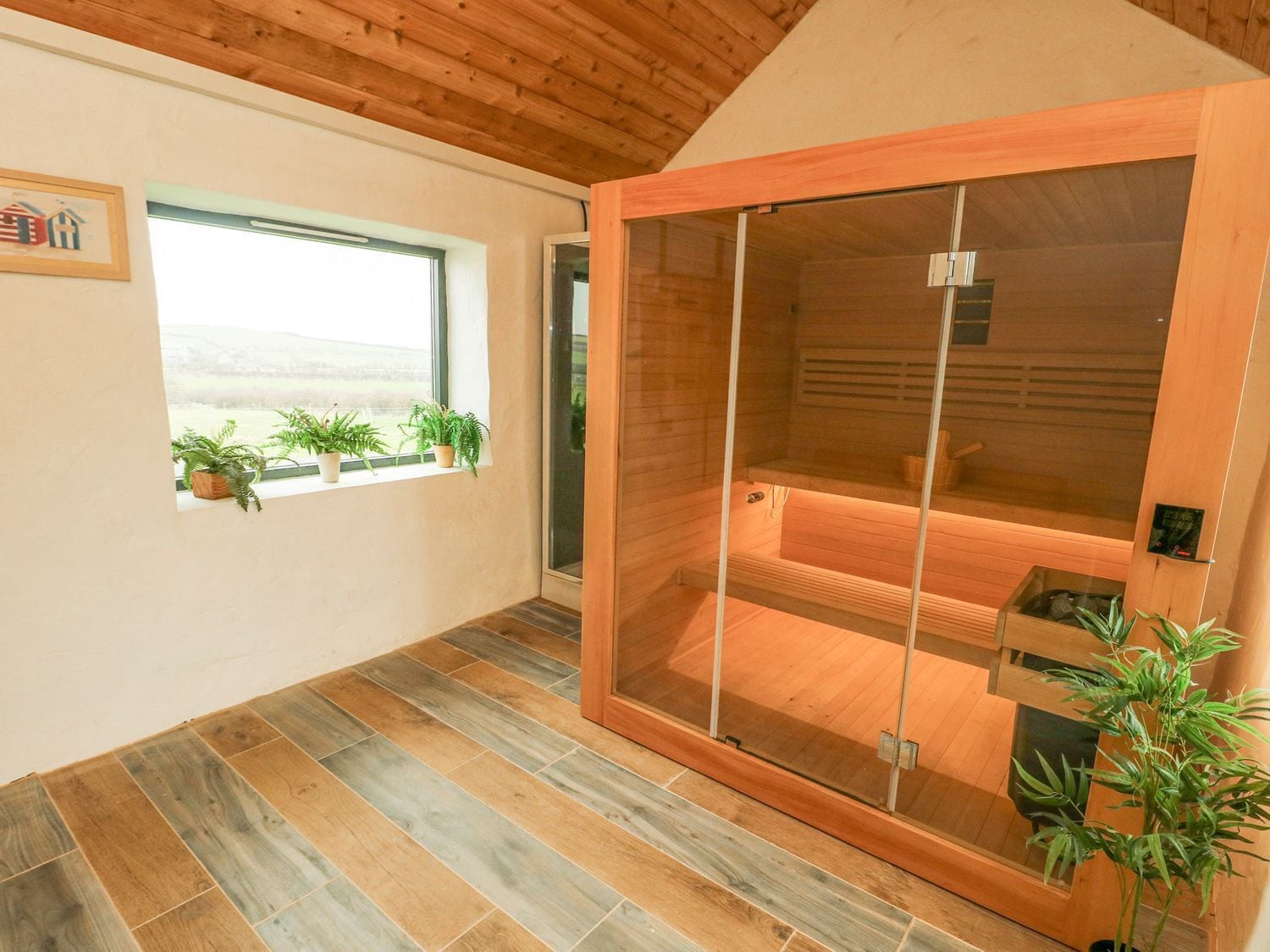 Un sauna avec une porte coulissante en bois, une fenêtre ornée de plantes et un sol carrelé.