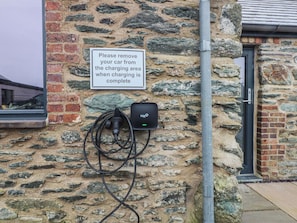 A charging station mounted on a stone wall with a sign instructing to remove the car after charging. - 2 Trem Y Mor (Holyhead)