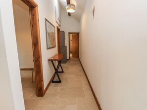 A narrow hallway with wooden doors, a small table, and a light fixture. - 2 Trem Y Mor (Holyhead)