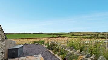 A stone building with a gravel patio and a view of rolling hills.