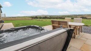 Un bain à remous avec vue sur un champ verdoyant et des collines en arrière-plan.
