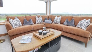 Un salon moderne avec un canapé aux lignes courbes, une table basse en bois et une vue sur la campagne.