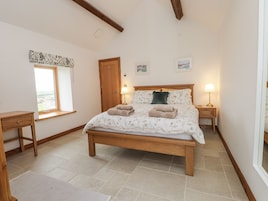 Un dormitorio con una cama de madera, una mesita de noche y una ventana, además de una puerta.