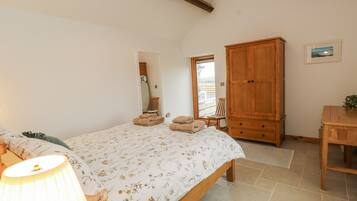 A bedroom with a bed, a wooden wardrobe, a chair, and a table.