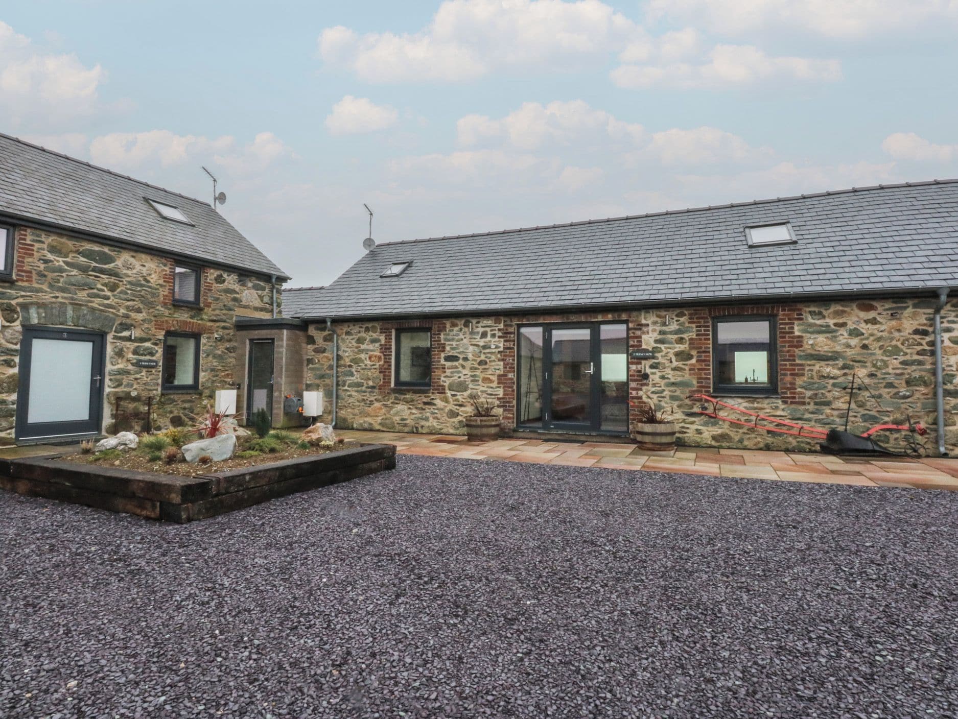 A stone building with a gravel driveway and a small garden area.
