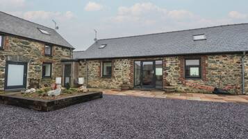 A stone building with a gravel driveway and a small garden area.