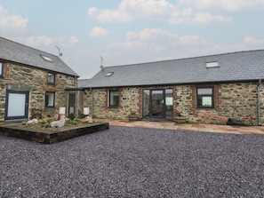 A stone building with a gravel driveway and a small garden area. - 2 Trem Y Mor (Holyhead)
