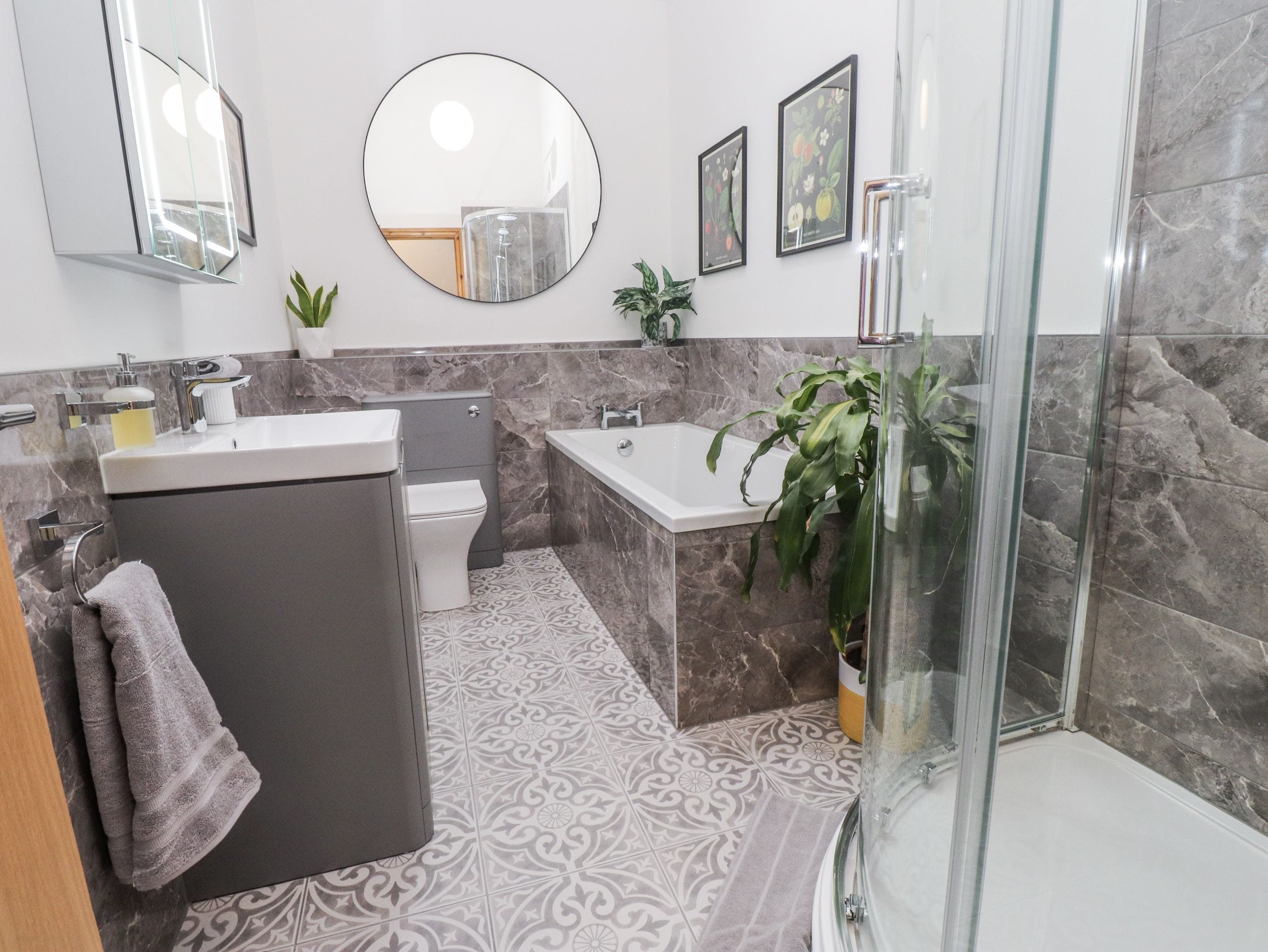 Un baño moderno con ducha, inodoro, lavamanos y un espejo grande.