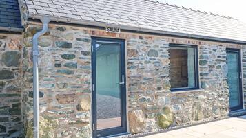 A stone building with a sign reading "SAUNA" above a door.