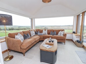 A modern living room with a brown sectional sofa, a coffee table, and a floor lamp. - 2 Trem Y Mor (Holyhead)
