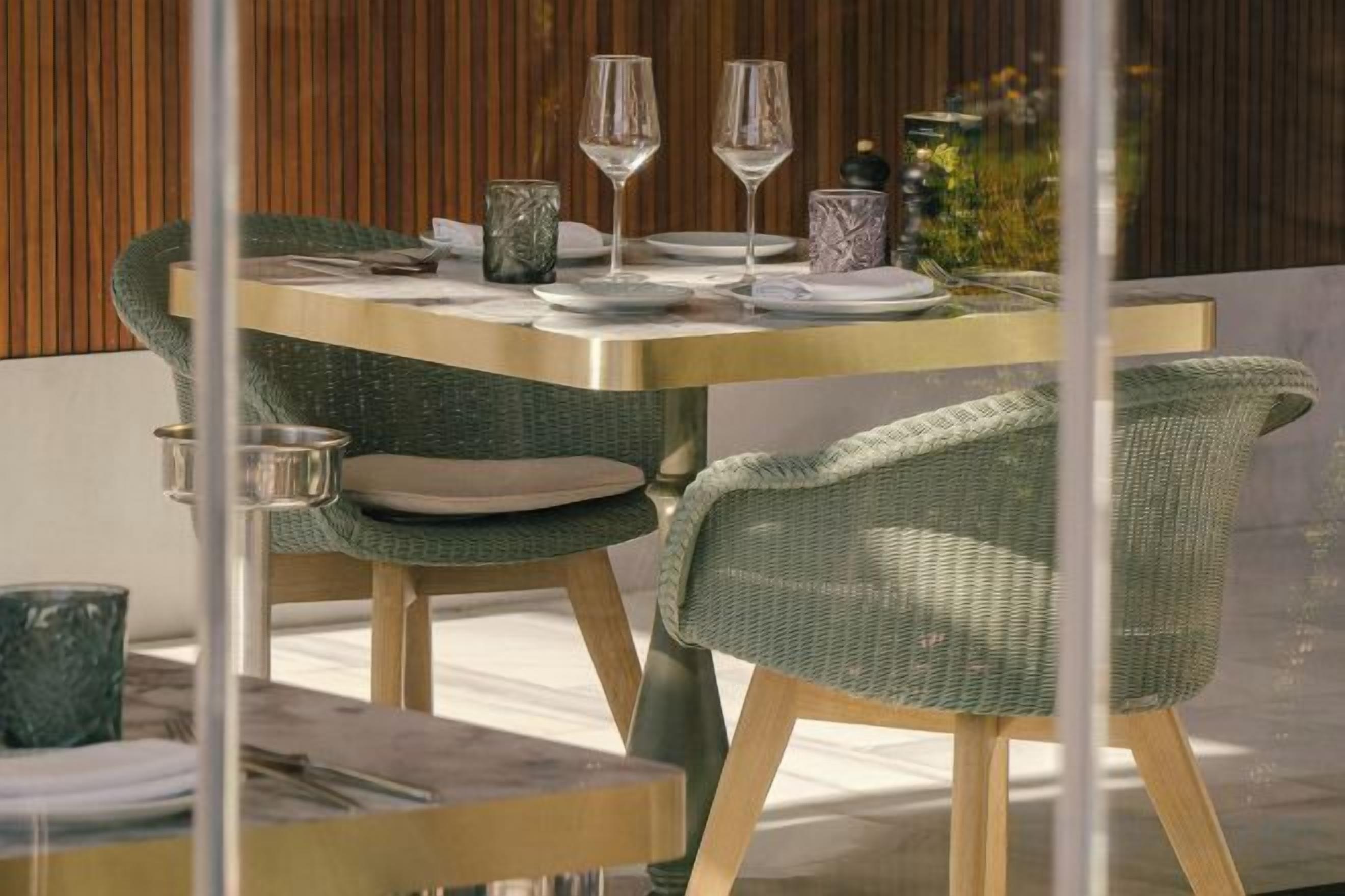 Una mesa de comedor con sillas, servida con platos, vasos y cubiertos.