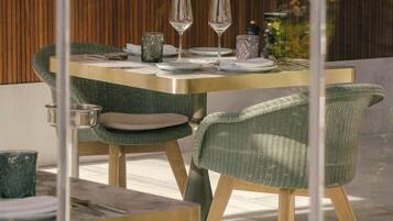 Una mesa de comedor con sillas, servida con platos, vasos y cubiertos.