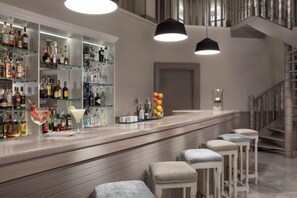 A bar area with shelves of bottles, a bar counter, and stools. - Palacio de Sancti Petri Gran Melia (Novo Sancti Petri)