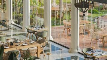 An indoor dining area with tables and chairs, large windows, and a view of the outdoor patio.