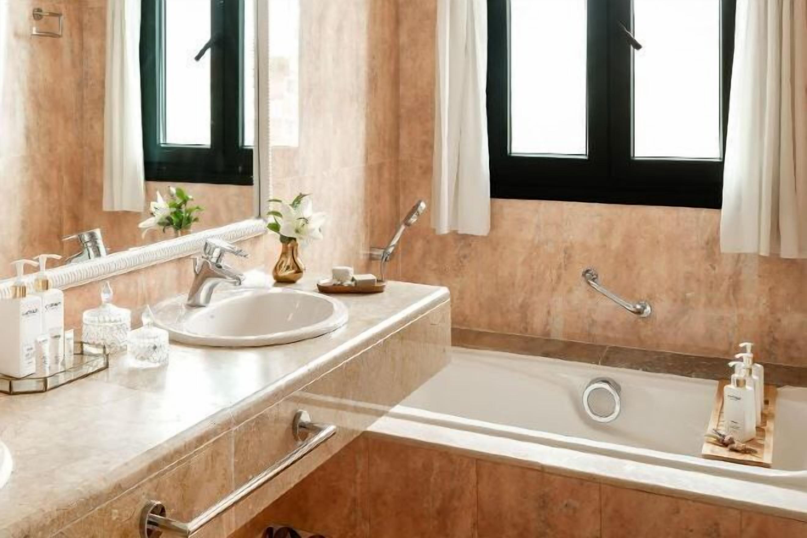 A modern bathroom with a large bathtub, a sink, and a mirror.