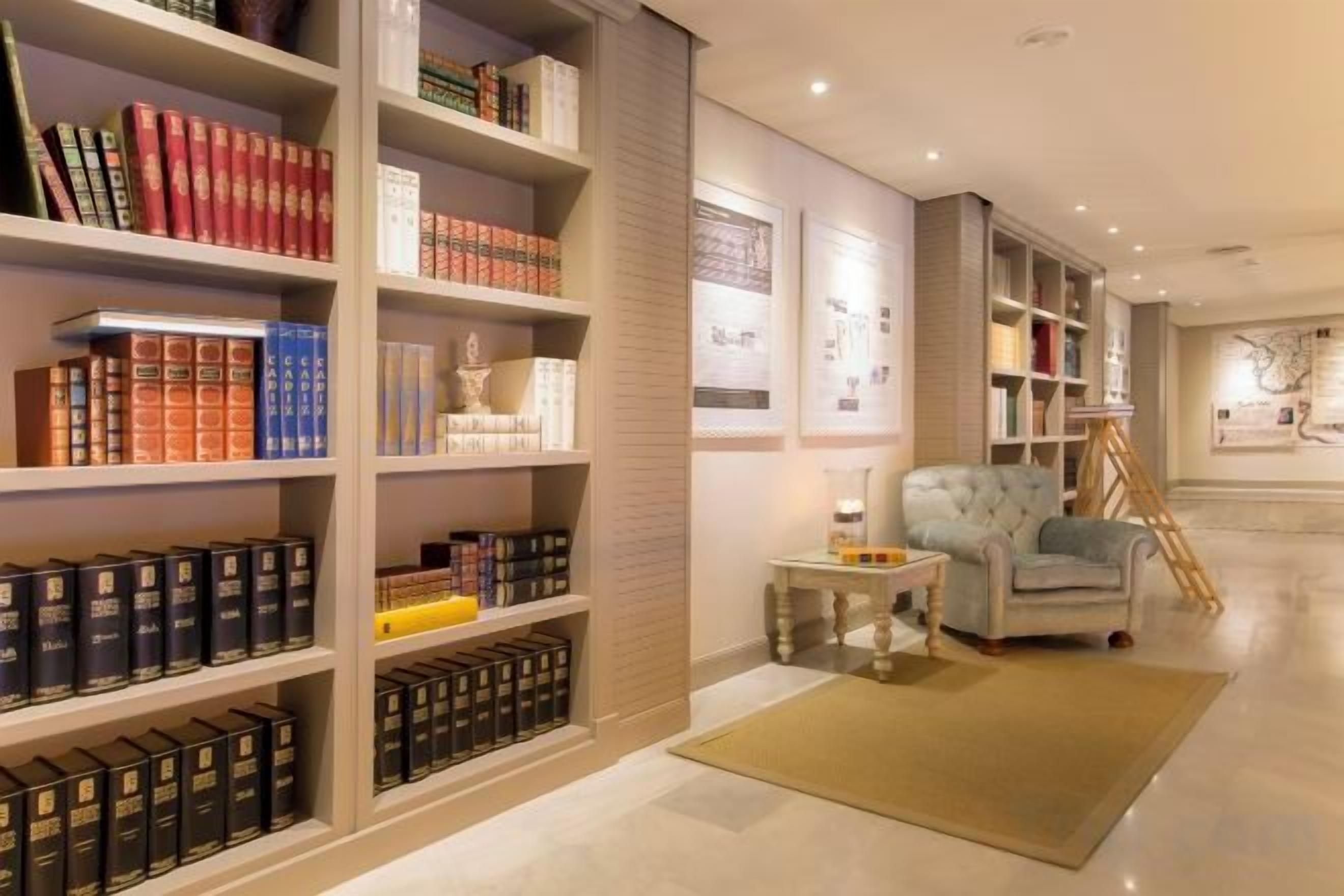 A library with bookshelves, a reading chair, and a small table.