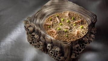 Un cuenco de madera tallada con superficie texturizada y una hendidura central, posiblemente para contener alimentos o bebidas.