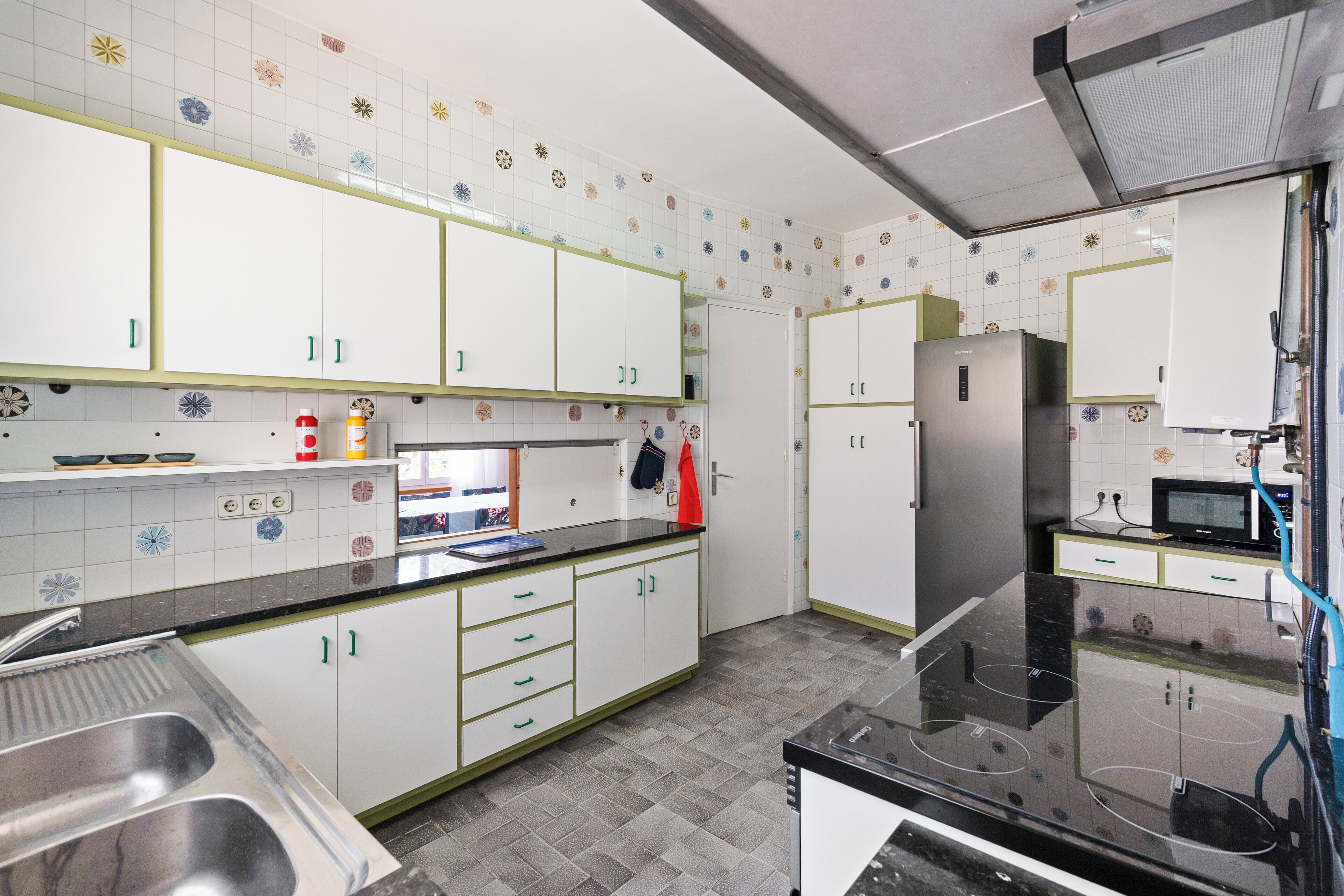 A modern kitchen with white cabinets, a black countertop, and a stainless steel sink.