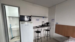 A compact room with a kitchenette, a bed, and a small bar area.