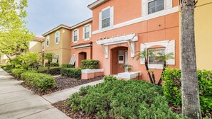 A row of two-story buildings with a consistent architectural style, featuring a flat roof and a central entrance with a white porch. - 3BR Encantada Townhome, Heated Pool (Kissimmee)
