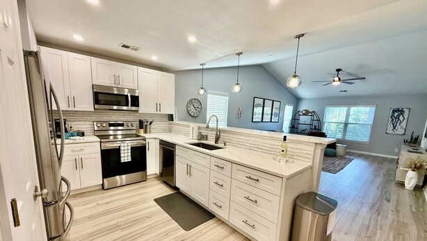 A modern kitchen with stainless steel appliances, white cabinetry, and a large island.