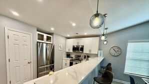 A modern kitchen with a central island, stainless steel appliances, and pendant lighting.