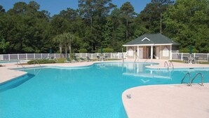 A clear blue swimming pool with a small pavilion and lounge chairs.
