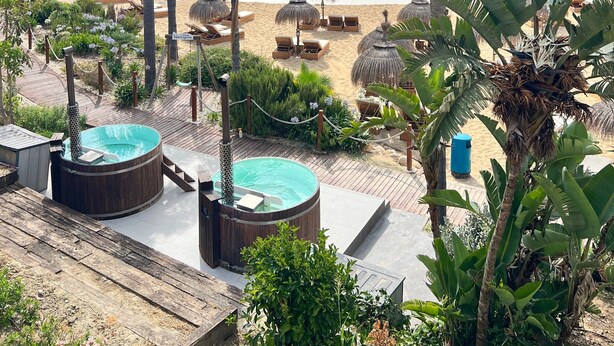 Un complexe hôtelier doté d’une piscine, de chaises longues et de palmiers.