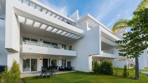 Une maison moderne à deux étages, dotée d’un vaste patio, de grandes fenêtres et d’une pelouse bien entretenue.