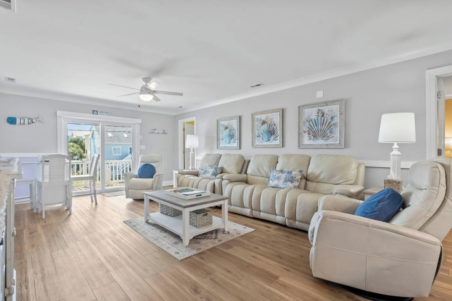 Un salon spacieux avec un ensemble de canapés beige, une table basse et un ventilateur de plafond.