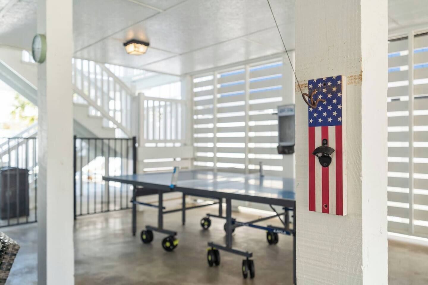 Ein großzügiger Innenbereich mit einem Tischtennisschrank, einer an der Wand befestigten amerikanischen Flagge und einer Treppe, die zu einer oberen Ebene führt.