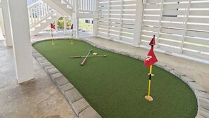 Un campo de mini golf con césped artificial verde, una bandera y palos de golf.