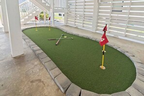 Un parcours de mini-golf avec un gazon artificiel vert, un drapeau et des clubs de golf.